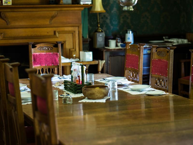 The long dining table laid for breakfast, with the green damask wall behind