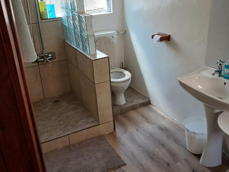 The Garden Room's shower room, with a tiled walk-in shower, basin and glass-block window