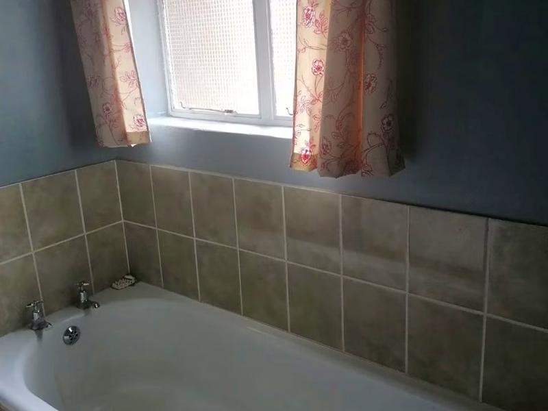 The Green Room's bathroom, with a tiled built-in bath below a curtained window