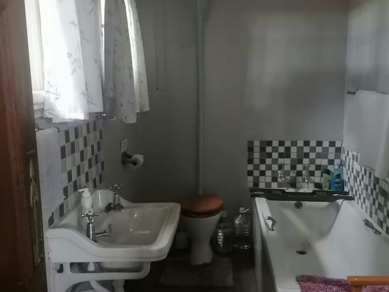 The Red Room's en-suite: a bath, pedestal basin and a high-level cistern, with black and white tiling