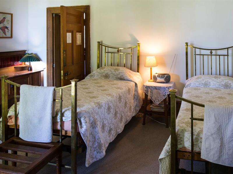 The Green Room: two brass poster single beds with a lamp between them and original wooden cupboards