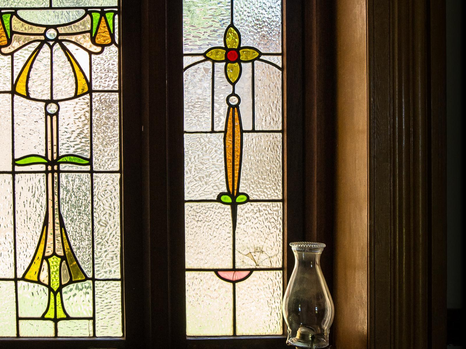 Two original stained glass window panels in amber, green and red, in an Art Nouveau design
